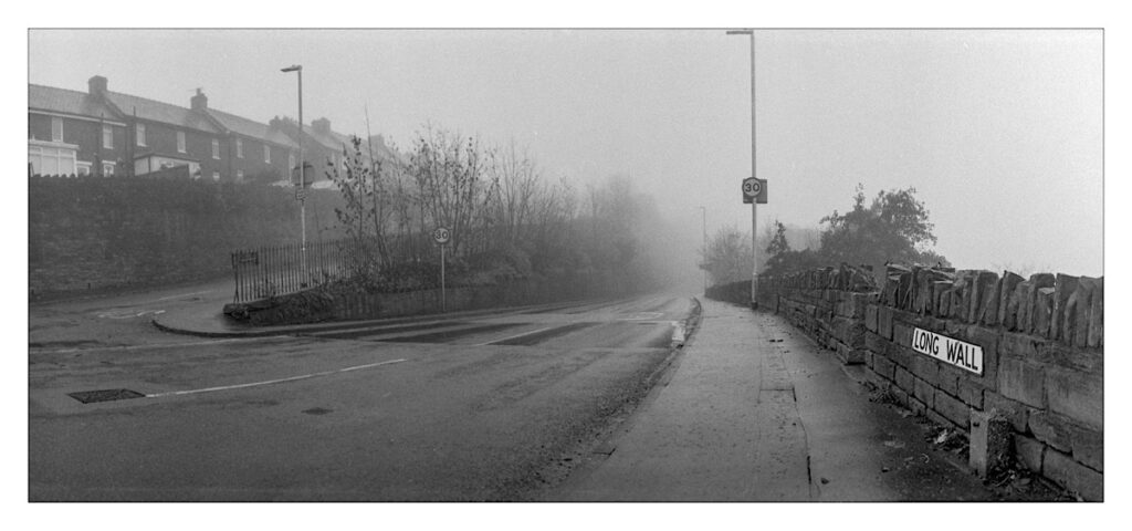 Black and white photograph of an urban street in fog