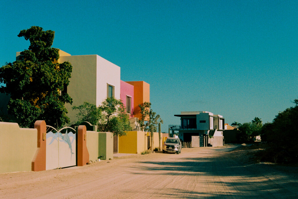 Street in Los Barriles Mexico. Square villas in white, orange, yellow and pink. Dirt road.
