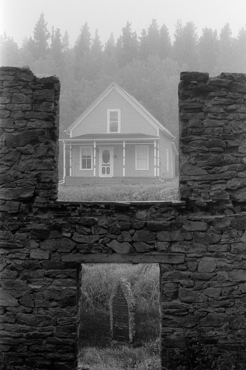 house and headstone view from window of ruined building