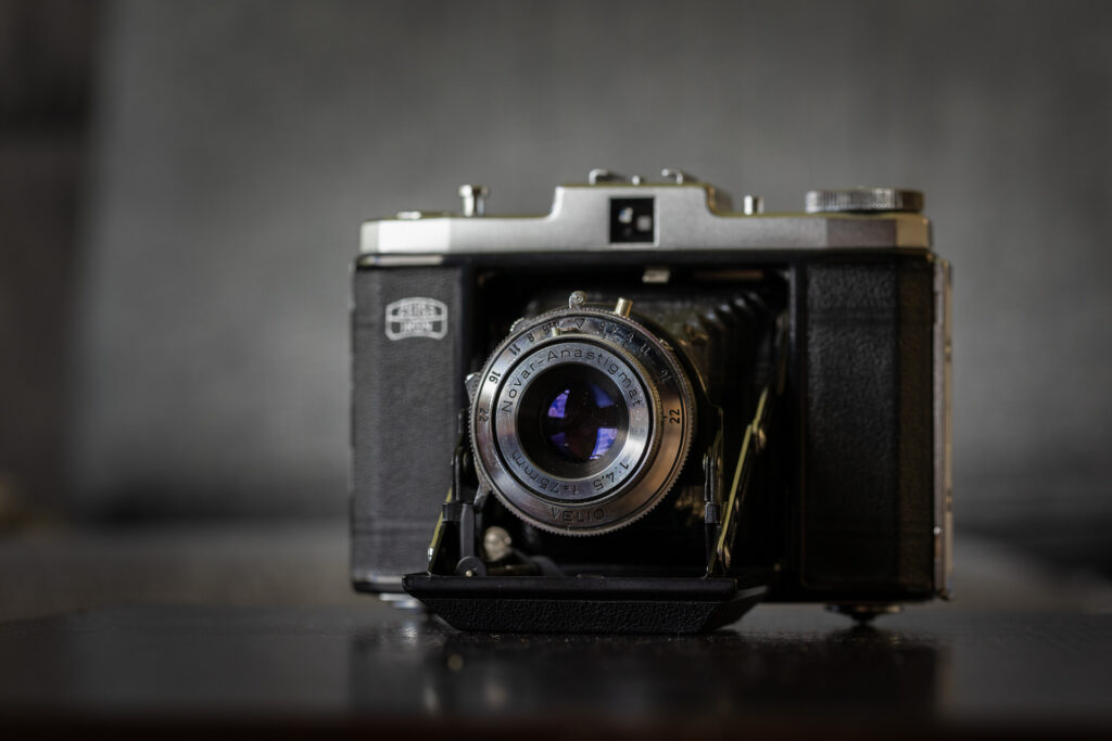 A photo of a vintage folding style camera, with the lens pointing to the viewer