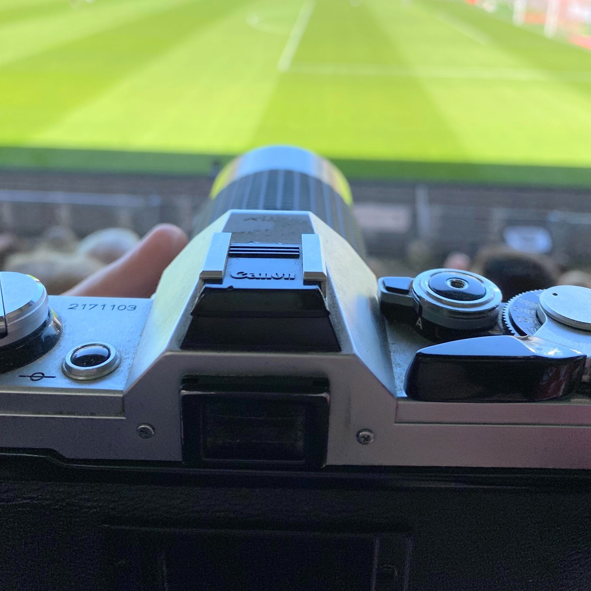 Canon AE-1 with zoom lens in focus, football pitch in the background