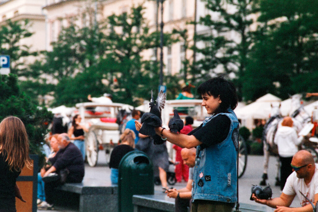 A girl feeding pigeons with one on her arm