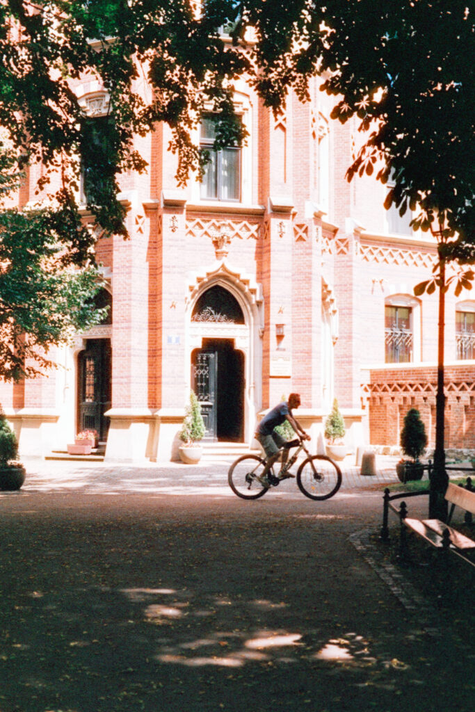 A cyclist riding past a sunlit building