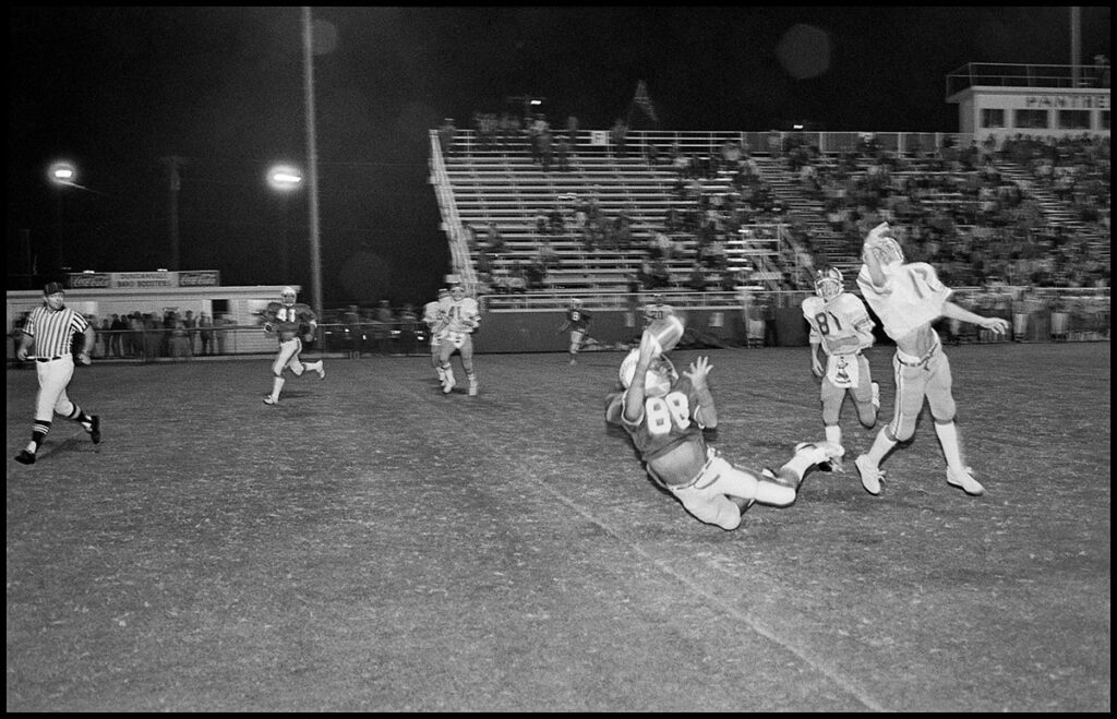 Duncanville football receiver making a diving catch while closely guarded by opponents defensive backs