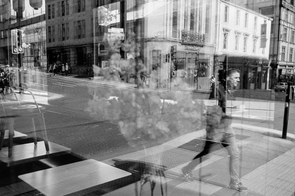 Reflection Of Person Walking Past Shop Window