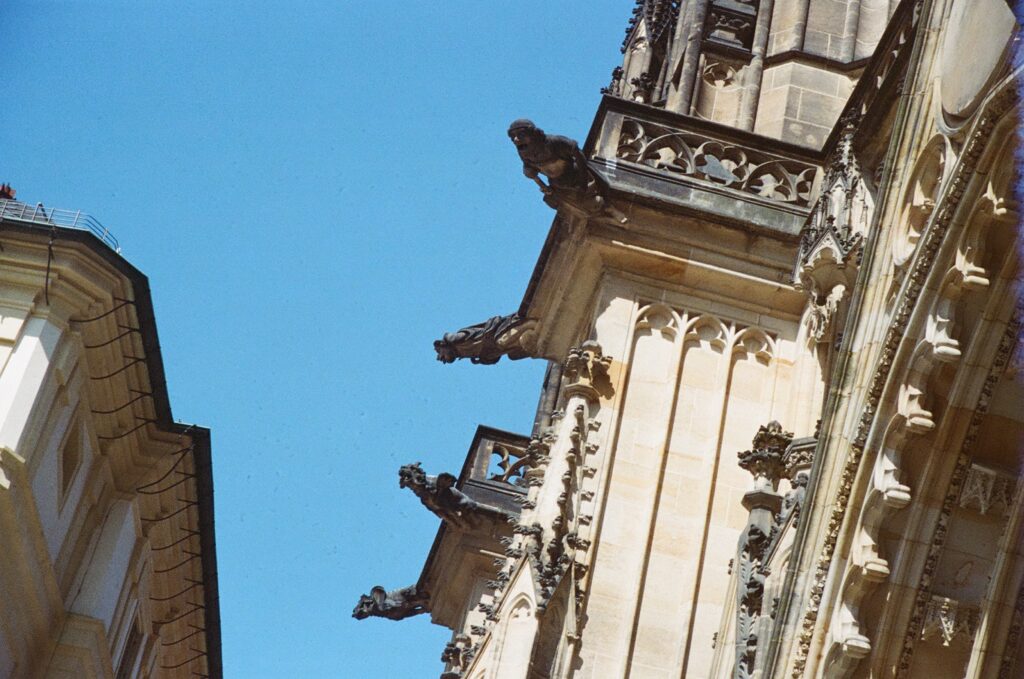 A picture of four gargoyles sticking out the side of an ornate building. There is the side of another building next to them.