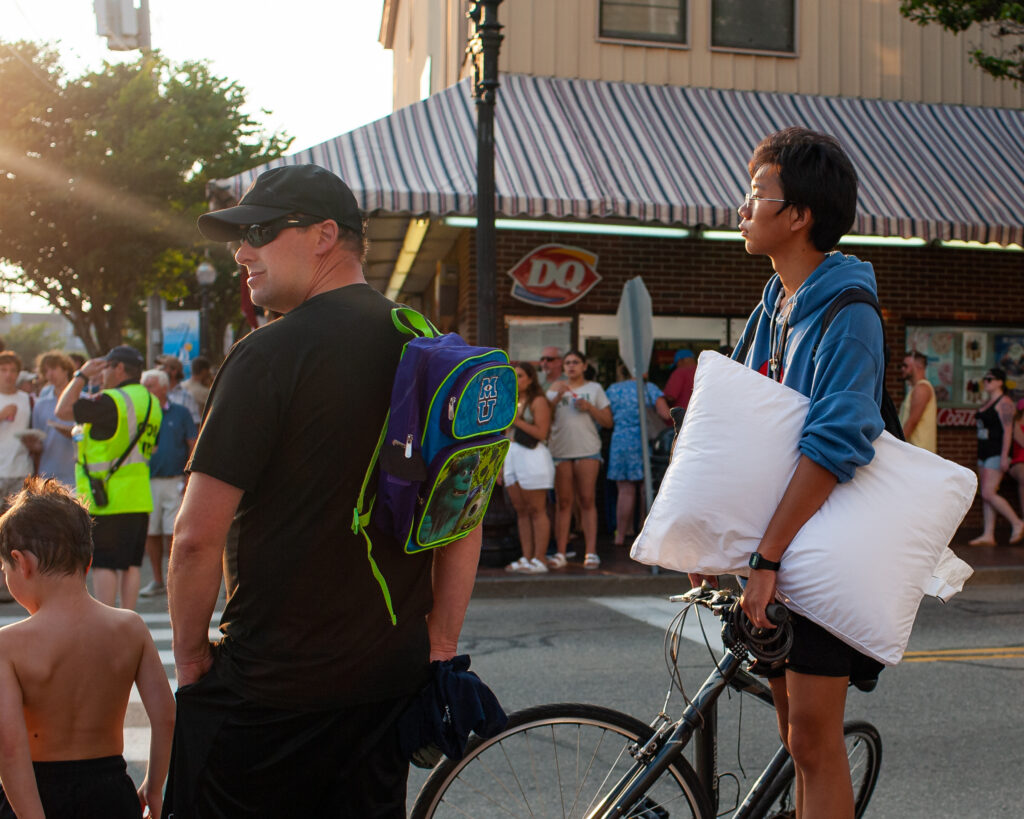 Younger guy standing near bike holding pillow.