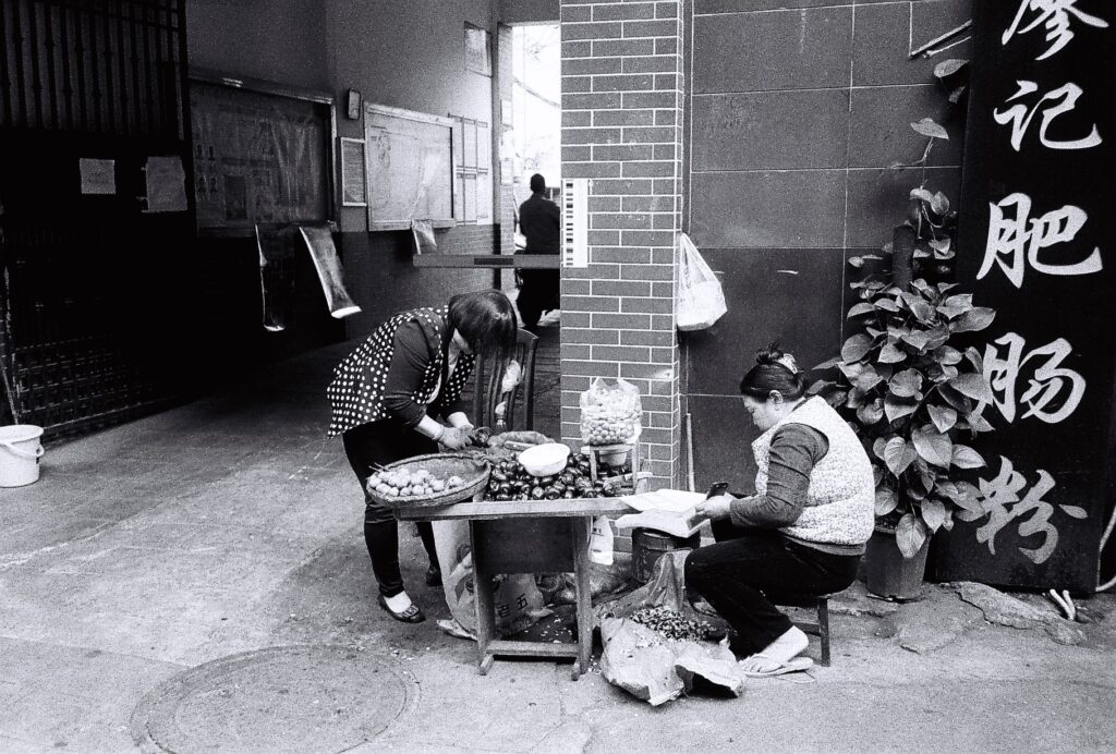 two women sat preparing vegetables.