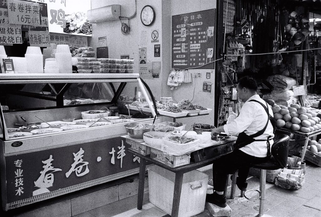 A man sitting with his back to camera making steamed buns.