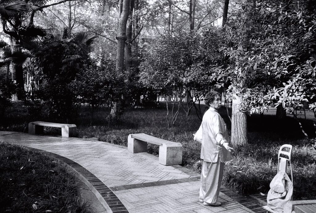 A woman standing on a path, exercising.