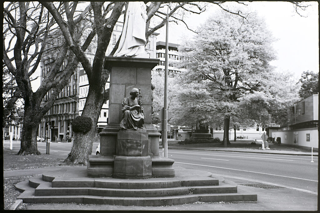 Base of Queen Victoria monument and business district buildings, Dunedin.