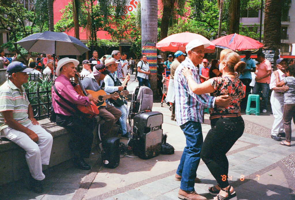 Color photograph of a couple dancing to the music of street performers in Medellin, Colombia