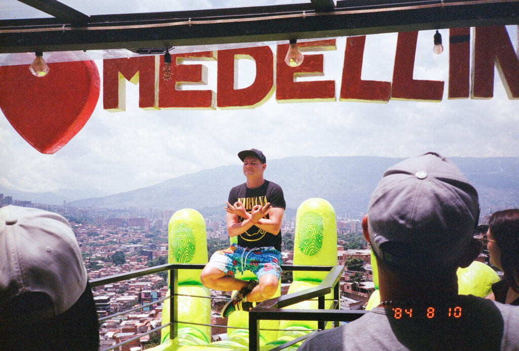 Color photograph of man in meditative pose high above Medellin, Colombia