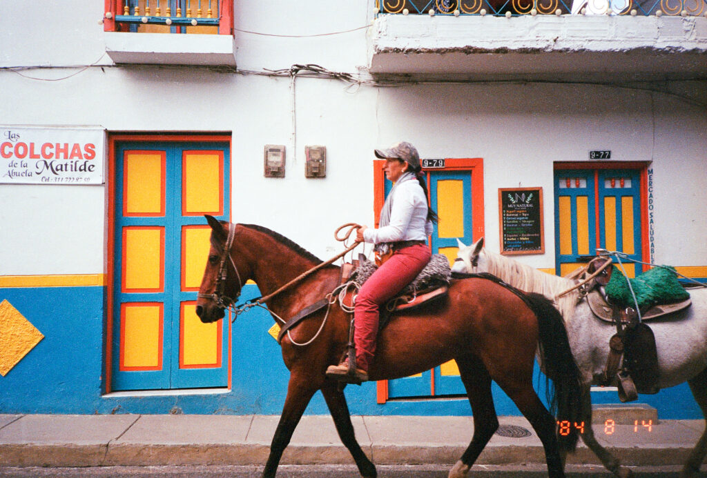 Color photograph of a women riding a horse in the street in Jardin, Colombia