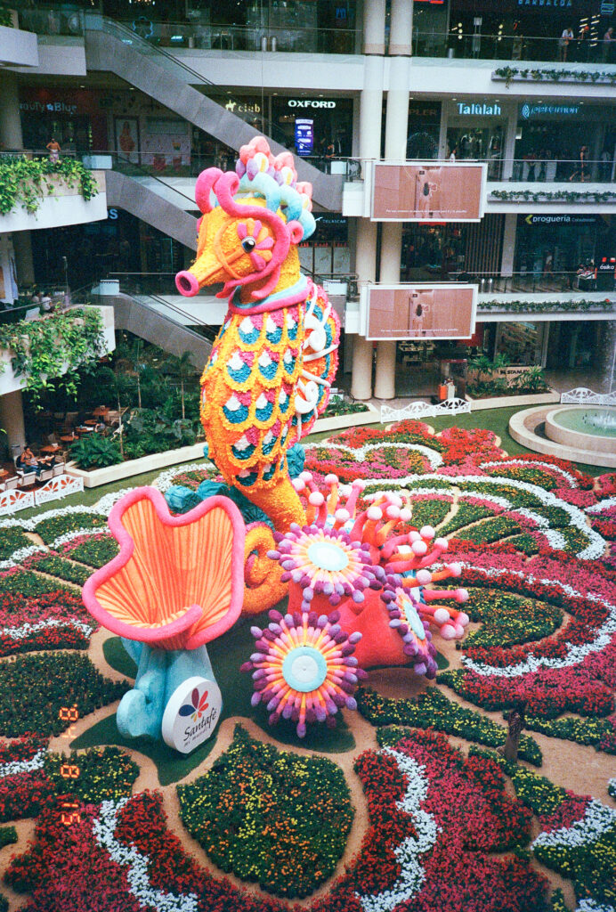 Color photograph of a large sea horse made of flowers inside a shopping mall in Medellin, Colombia