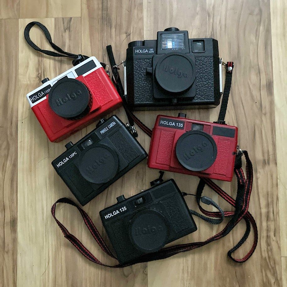 five plastic Holga cameras on a wooden floor