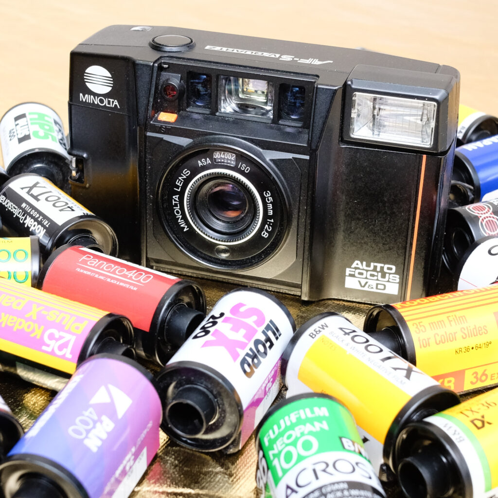 Photograph of a Minolta AF-Sv camera surrounded by rolls of film