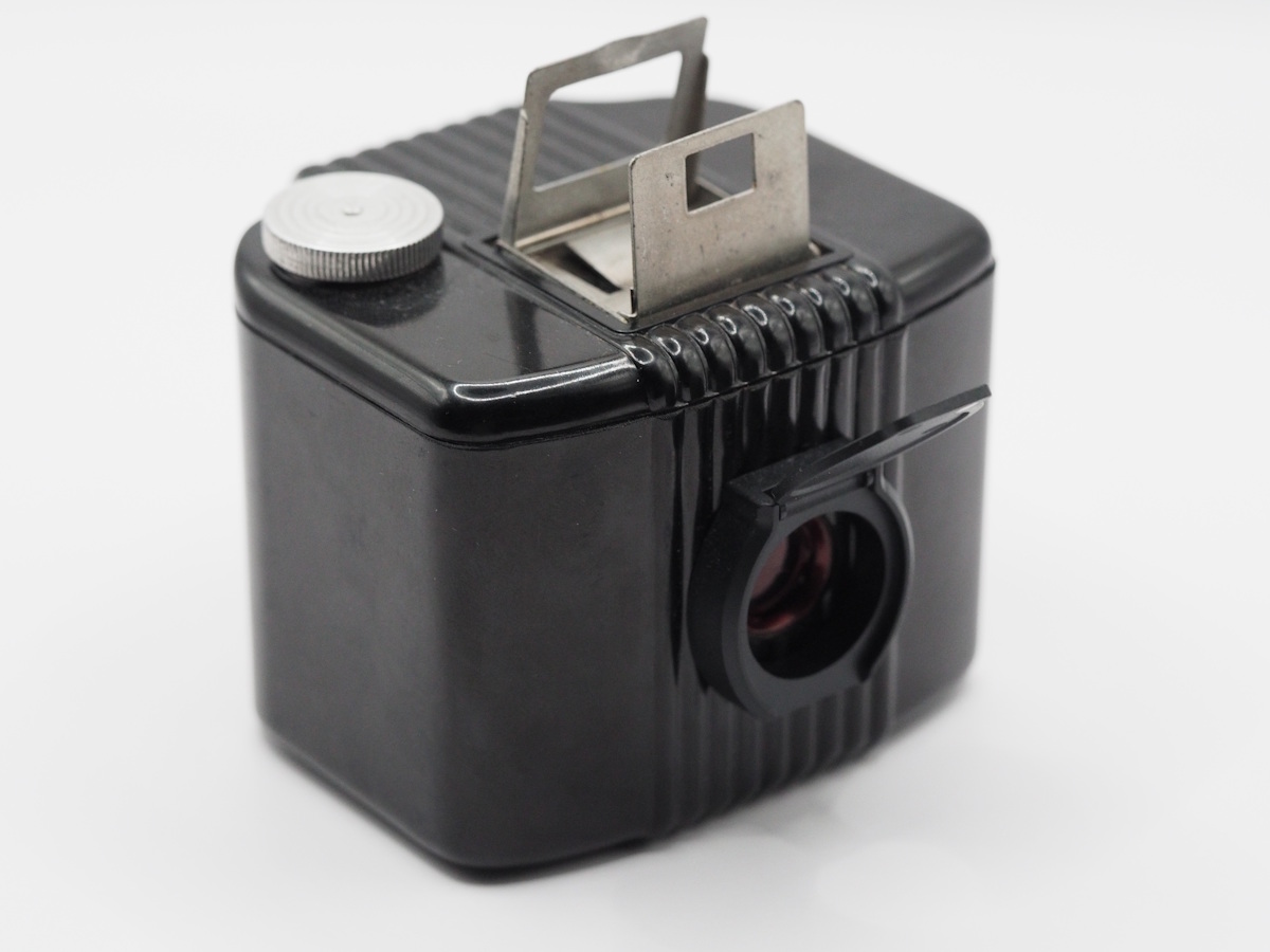 A black box camera with a webcam cover over its red window